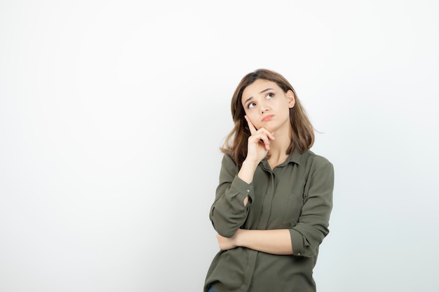 Adorável jovem com roupa casual em pé e pensando. Foto de alta qualidade