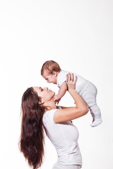 Adorável jovem mãe segurando seu bebê e olhando para ele em um fundo branco