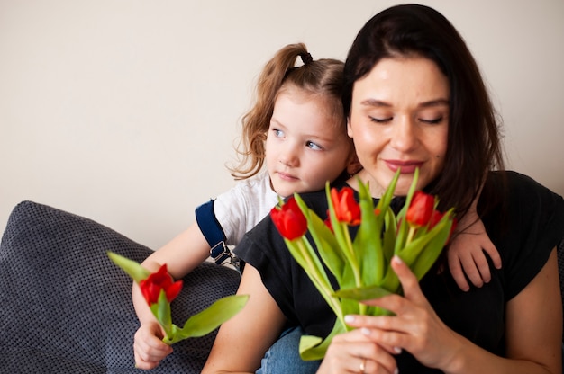 Adorável jovem mãe surpreendente com flores