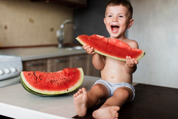 Adorável jovem rapaz comendo melancia