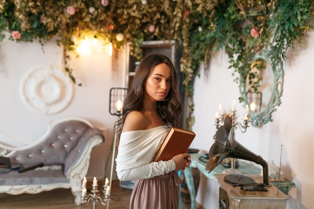 Adorável jovem segurando seu livro e olhando para a câmera com confiança Foto de alta qualidade