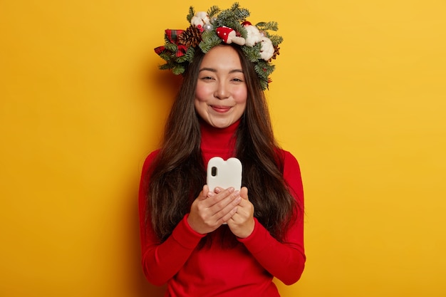 Adorável jovem sorrindo agradavelmente usando coroa de flores festiva na cabeça