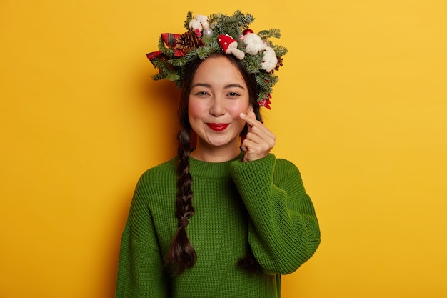 Adorável jovem sorrindo agradavelmente usando coroa de flores festiva na cabeça