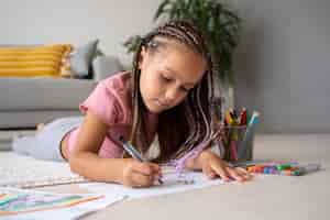 Foto grátis adorável menina desenhando no papel em casa