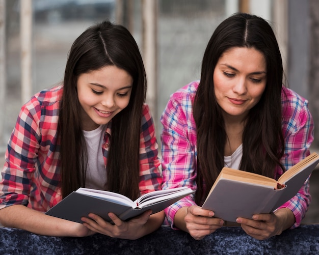 Adorável menina e mulher lendo livros