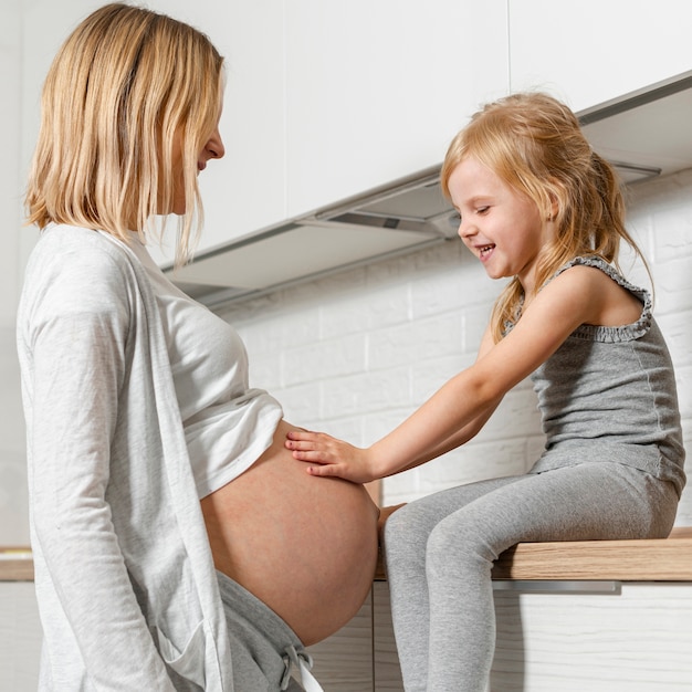 Foto grátis adorável menina olhando a barriga da mãe