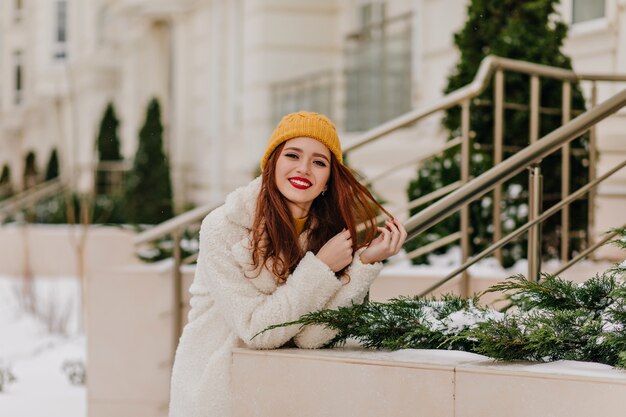 Adorável menina ruiva com chapéu, expressando emoções positivas. Lindo modelo feminino relaxante no inverno.