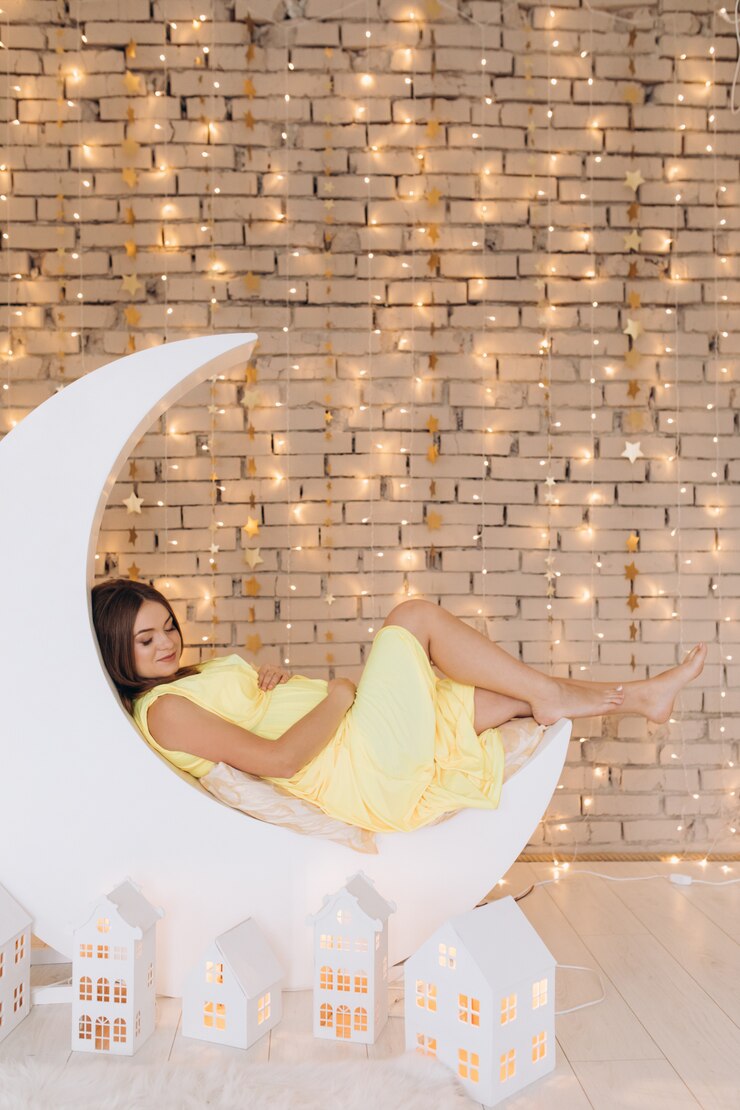Foto grátis adorável mulher grávida no vestido amarelo encontra-se na lua antes de uma parede