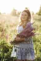 Foto grátis adorável mulher loira de vestido azul atravessa o campo de flores de lavanda violeta