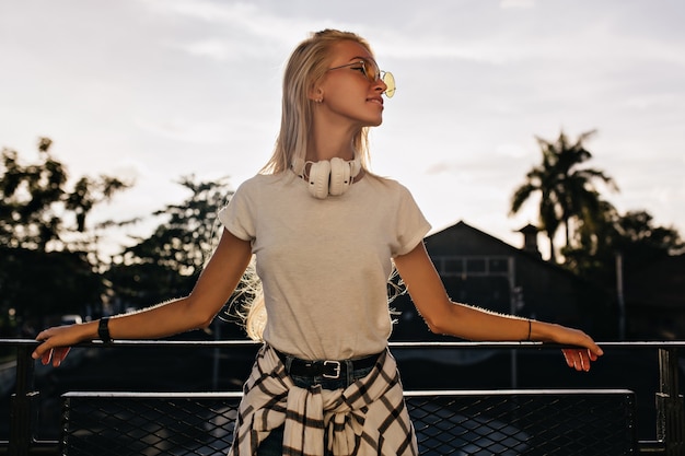 Adorável senhora caucasiana em roupas da moda, olhando para longe enquanto posava à noite.