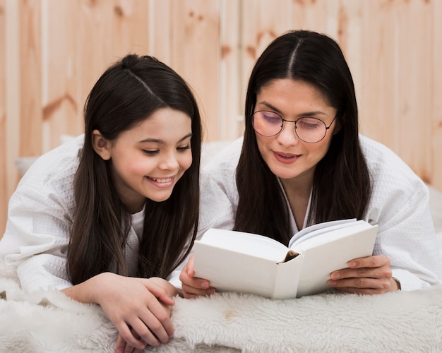 Adulta mulher lendo um livro com jovem