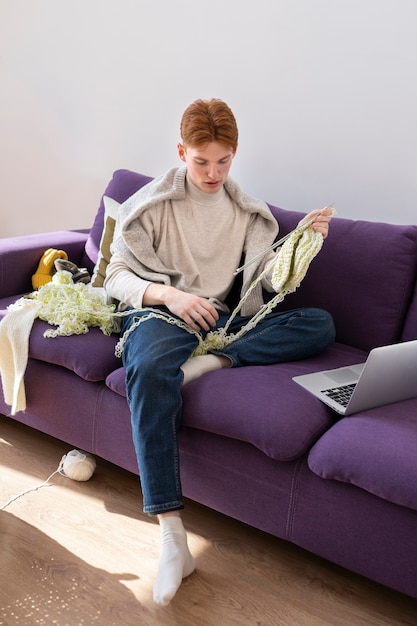 Adulto jovem tricô em casa