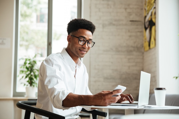 Africano jovem bonito sentado coworking