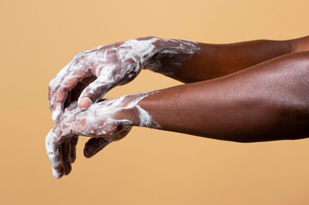 Africano lavando as mãos com sabonete isolado em laranja