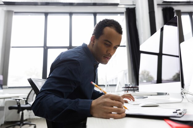 Afro-americano empresário fazendo anotações enquanto está sentado em sua mesa