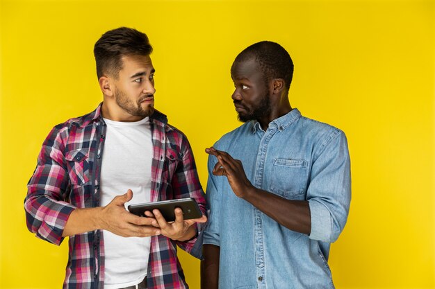 Afroamerican guy está provando algo para europeu guy em camisas informais