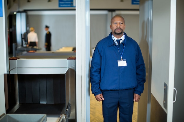 Agente de segurança do aeroporto parado na porta do detector de metais