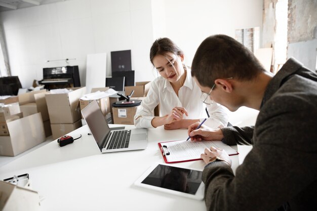 Agente imobiliário feminino mostrando a nova casa para um jovem depois de uma discussão sobre os planos da casa, movendo-se, novo conceito de casa