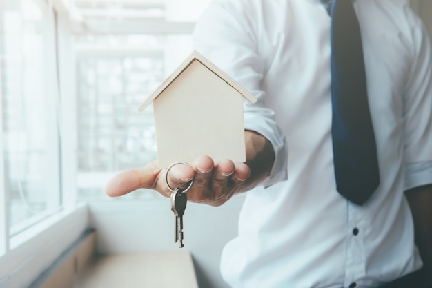 Foto grátis agente manual com casa na palma da mão e chave no dedo.