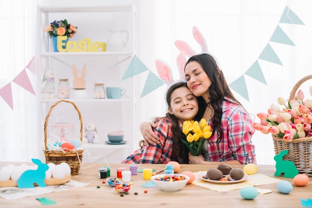 Agradável mãe abraçando sua filha comemorando o dia da páscoa