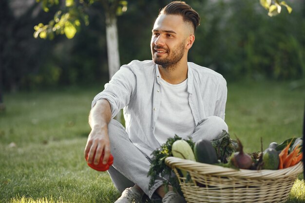 Agricultor alegre com vegetais orgânicos no jardim. Vegetais orgânicos misturados em cesta de vime.