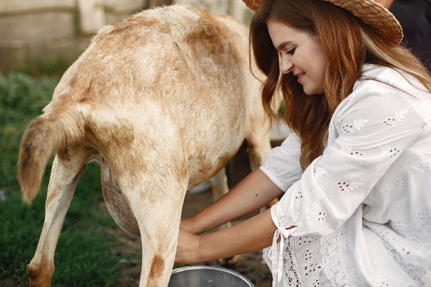 Foto grátis agricultor de menina com cabra branca. mulher e grama verde pequena cabra. fazenda ecológica. fazenda e conceito de agricultura. animais da aldeia. menina para molk uma cabra.