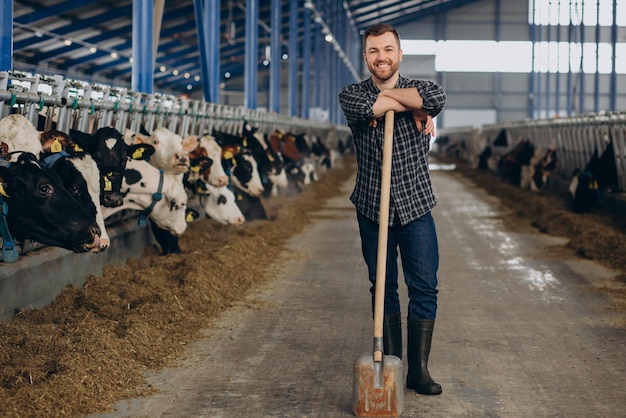 Agricultor no estábulo com forcado limpando