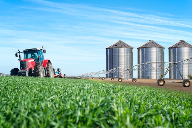 Agricultura e conceito de produção de alimentos com silos de máquina de trator e sistema de irrigação