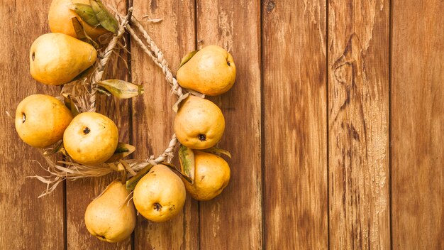 Ainda vida com peras amarelas na parede de madeira compensada