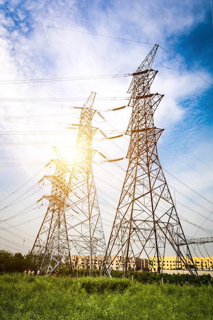 Ajuste do sol atrás da silhueta das torres de eletricidade