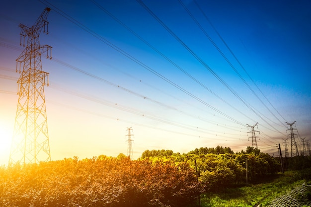 Ajuste do sol atrás da silhueta das torres de eletricidade