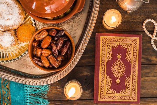 Alcorão e velas perto de comida árabe