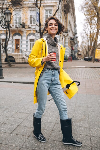 Alegre bela jovem vestida com botas de borracha