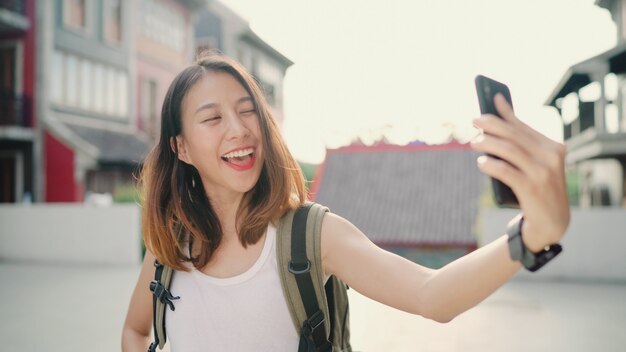 Alegre bonita jovem mochileiro asiáticos blogueiro mulher usando smartphone tomando selfie