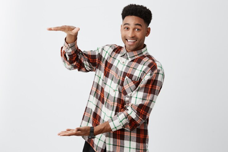 Foto grátis alegre cara de pele negra madura com penteado afro em camisa quadriculada casual gesticulando com as mãos, finge segurando uma caixa grande com expressão feliz.