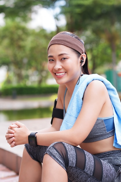 Alegre desportista asiática sentado no parque