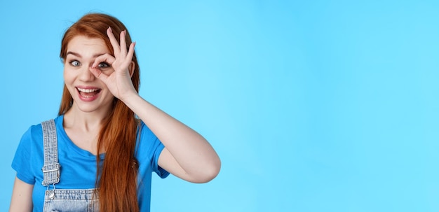 Foto grátis alegre e otimista ruiva europeia, sinta-se sortuda, inspirada, olhe através do círculo, bem no olho, sorrindo