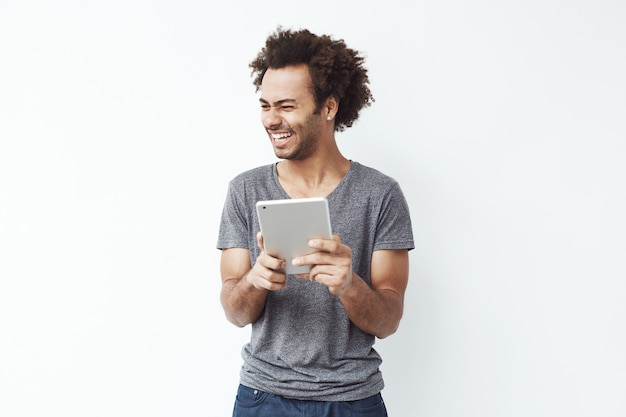 Alegre homem africano rindo segurando o tablet.