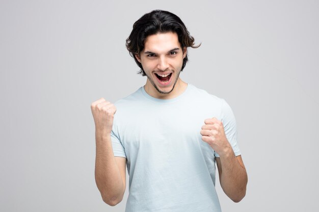 alegre jovem bonito olhando para a câmera mostrando sim gesto isolado no fundo branco