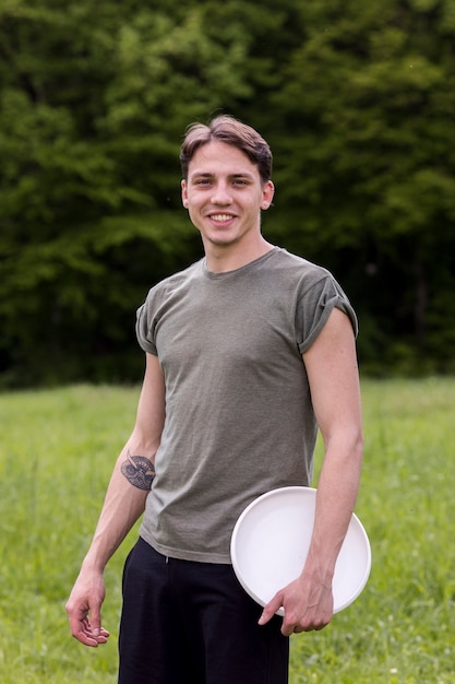 Alegre jovem macho em pé com frisbee na natureza