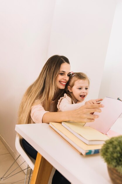 Foto grátis alegre mãe e filha lendo livro na mesa