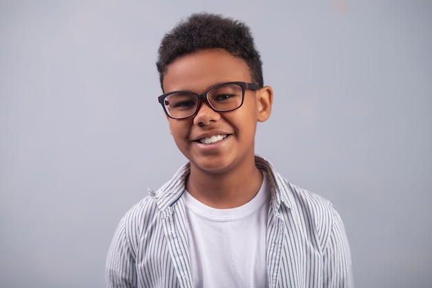 Alegre menino bonito em óculos posando para a câmera