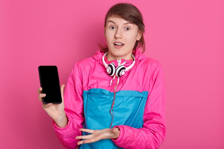 Foto grátis alegre muito jovem desportista caucasiana segurando o smartphone de tela em branco