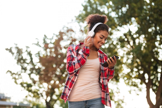 Foto grátis alegre mulher africana jovem caminhando ao ar livre