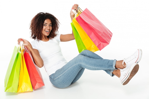 Alegre mulher africana jovem segurando sacolas de compras.