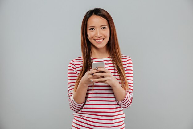 Alegre mulher asiática jovem conversando por telefone