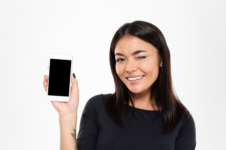 Foto grátis alegre mulher asiática jovem mostrando a tela do telefone móvel