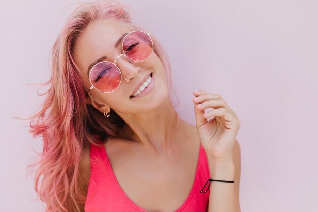 Alegre mulher caucasiana com cabelo rosa, posando com um sorriso fofo.