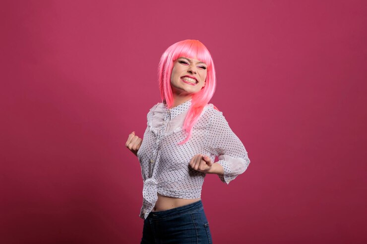 Foto grátis alegre mulher confiante comemorando grande vitória e sucesso, posando na frente da câmera sobre fundo rosa. sentindo-se feliz e animado com a conquista e o maravilhoso triunfo, estilo vencedor.
