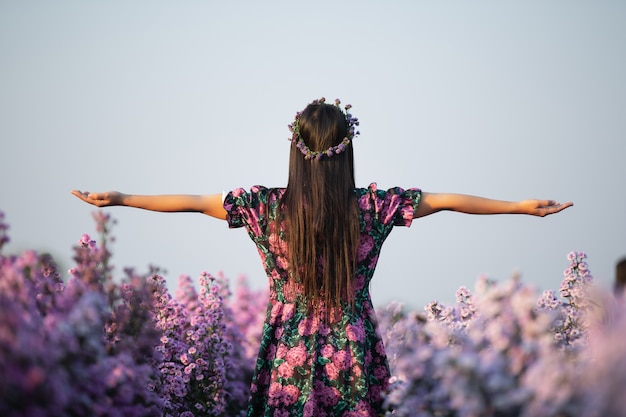 alegre mulher de vestido roxo entre da flor roxa margaret